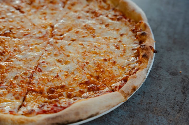A close-up view of a whole cheese pizza, showcasing its golden-brown crust and melted cheese toppings