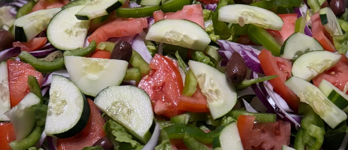 Fresh vegetable salad with sliced cucumbers, tomatoes, red onion, and green peppers