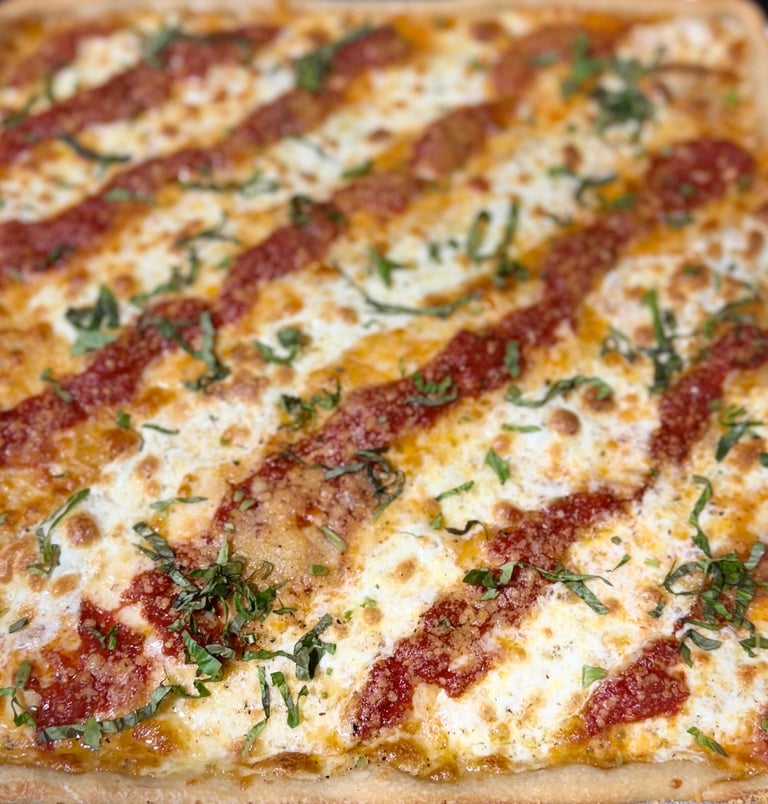 Baked pasta dish with alternating stripes of melted cheese and tomato sauce, garnished with fresh herbs